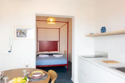 a room with a bed and a kitchen with a table at Piricù Apartments in Castellammare del Golfo