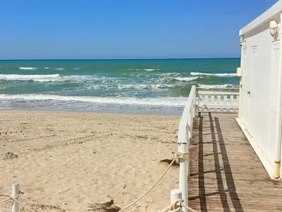 a building on the beach next to the ocean at Riva Home Il tuo angolo di paradiso in Sicilia ti aspetta! Prenota ora e vivi la magia del Mediterraneo!