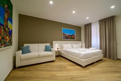 a bedroom with a white bed and a white couch at B&B Maqueda - Room & Suite in Palermo