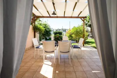 a patio with a table and chairs under a pergola at Villa levante Macari in Macari