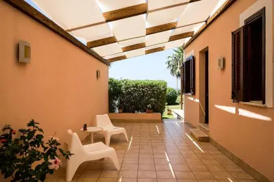 a patio with white chairs and a table in a building at Villa Grecale Macari in Macari