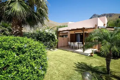 a house with a palm tree and a yard at Villa Grecale Macari in Macari
