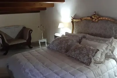 a bedroom with a large bed and a chair at Appartamento uso turistico Villa Barbara in Carini