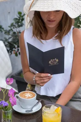 a woman holding a book and a cup of coffee at Palazzo Ventimiglia Lodge & Suites in Palermo