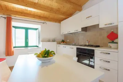 a white kitchen with a bowl of fruit on a counter at Vito nel Baglio in Scopello
