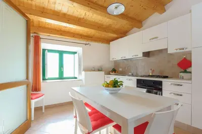 a kitchen with white cabinets and a table with chairs at Vito nel Baglio in Scopello