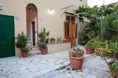 a house with potted plants and a green door at Vito nel Baglio in Scopello