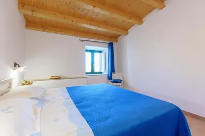 a bedroom with a blue and white bed with a window at Vito nel Baglio in Scopello