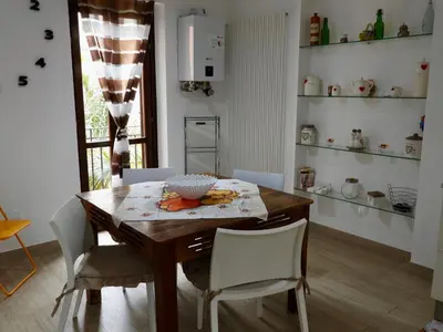 a dining room with a wooden table and white chairs at A Casa di Eli Apartment in Palermo
