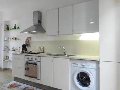 a white kitchen with a washing machine and a sink at A Casa di Eli Apartment in Palermo
