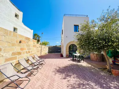 a patio with chairs and a table and a building at Magaggiari Reef in Cinisi