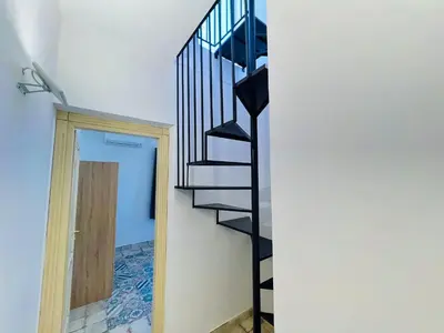 a black spiral staircase in a room with a door at Magaggiari Reef in Cinisi