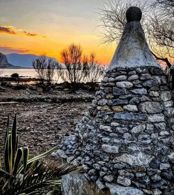 a stone wall in a field with a sunset in the background at Marea in Palermo