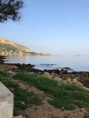 a view of a beach with the ocean and mountains at Marea in Palermo
