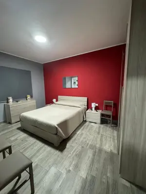 a bedroom with a bed and a red wall at RESIDENCE GORDON in Carini