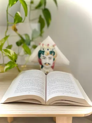 an open book on a table with a vase at Attico Belvedere in Palermo