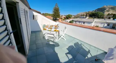 a balcony with a table and chairs on a roof at mansarda beach Mondello in Palermo