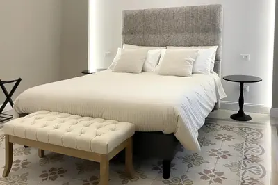 a bedroom with a large bed with a bench next to it at Dimora Borghese “Whitaker” in Palermo