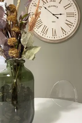 a clock hanging on a wall next to a vase with flowers at Dimora Borghese “Whitaker” in Palermo