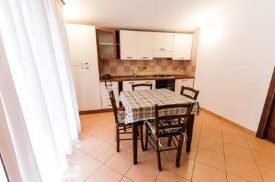 a kitchen with a table and chairs in a room at Trinity Apartments in Castellammare del Golfo