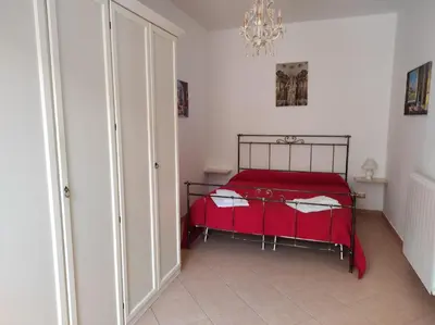 a bedroom with a red bed with a red blanket at Trinity Apartments in Castellammare del Golfo