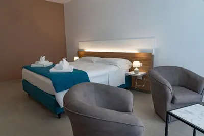 a hotel room with a bed and two chairs at B&B Alba in Terrasini