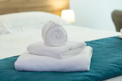 a stack of white towels on a bed at B&B Alba in Terrasini
