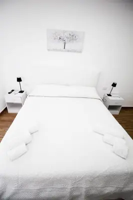 a white bedroom with a large white bed with two lamps at La chiave dei sogni in Palermo