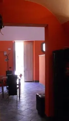 a living room with orange walls and a table and chairs at Dammuso SoleLuna. in Terrasini