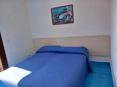 a bedroom with a blue bed with a picture of a motorcycle at Casa Orchidea Bianca in San Vito lo Capo