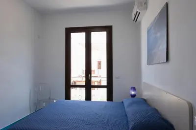 a bedroom with a blue bed and a window at Casa Orchidea Bianca in San Vito lo Capo