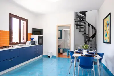 a kitchen with blue tile floors and a staircase at Casa Orchidea Bianca in San Vito lo Capo
