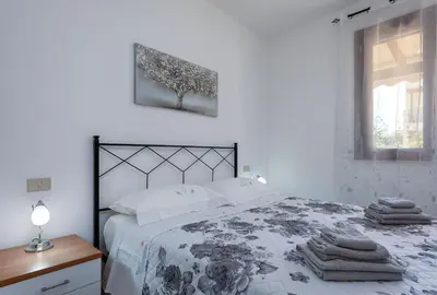 a white bedroom with a bed and a window at Bedda Luna Villa in San Vito lo Capo