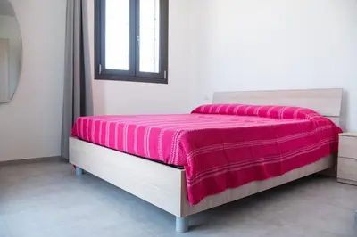 a bed with a pink blanket on it in a room at Villa Marica in Partinico