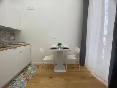 a white kitchen with a table and chairs in a room at La Piccola Formica Home in Palermo