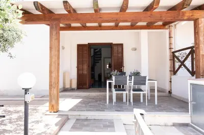 a patio with a table and chairs under a wooden pergola at Casa Orchidea Nera in San Vito lo Capo