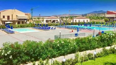 a large swimming pool with blue chairs in a resort at Casa Vacanze Isabella in Campofelice di Roccella