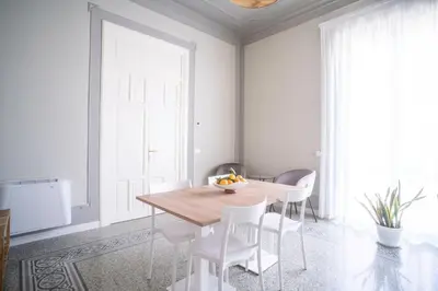 a dining room with a wooden table and white chairs at B&B Handy Palermo in Palermo
