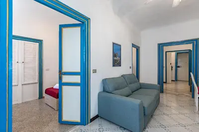 a living room with a blue chair and a mirror at Piazza Pretoria & Quattro Canti Roomy Flats with Balconies in Palermo