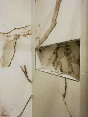 a bathroom with white marble walls and a shelf at wood & white home in Palermo