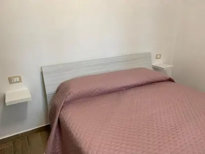 a bedroom with a bed with a pink comforter at La Villa degli Ulivi - Apartments in Castellammare del Golfo