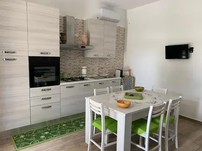 a kitchen with a white table and chairs in a kitchen at La Villa degli Ulivi - Apartments in Castellammare del Golfo