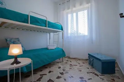 a bedroom with a bunk bed and a table with a lamp at Sea Air - Aria di Mare in Casteldaccia