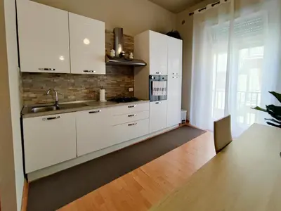 a kitchen with white cabinets and a wooden floor at ALP House in Palermo