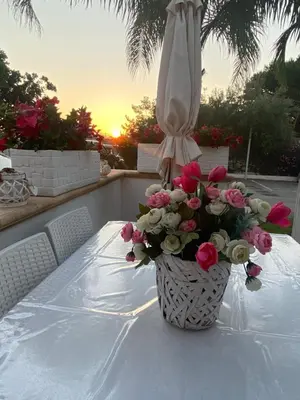 a vase of flowers sitting on a table with an umbrella at Le Palme House Isola delle Femmine in Isola delle Femmine