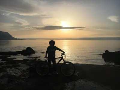 a boy is standing on a bike on the beach at Le Palme House Isola delle Femmine in Isola delle Femmine