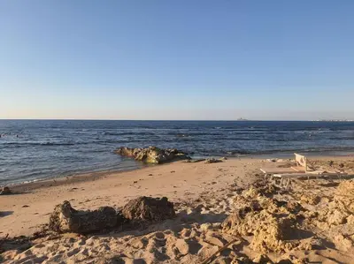 a sandy beach with a chair and the ocean at Casa Poseidonia - intero alloggio in riva al mare in Carini