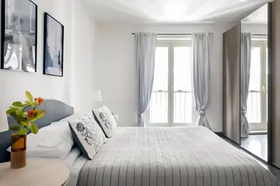 a white bedroom with a large bed and a table at Vicolo Paternò Apartments in Palermo