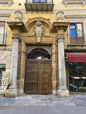 a building with a large wooden door with two columns at Pia's Home in pieno centro storico in Palermo