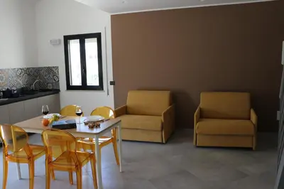a living room with a table and chairs and a kitchen at Elimi Home Appartamenti in Nuova Gibellina